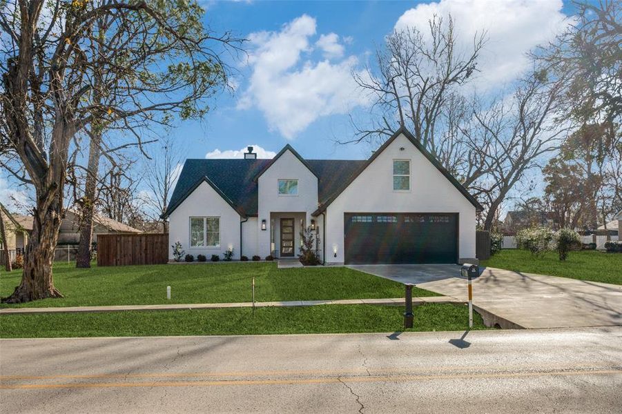 View of front facade featuring a front yard and a garage