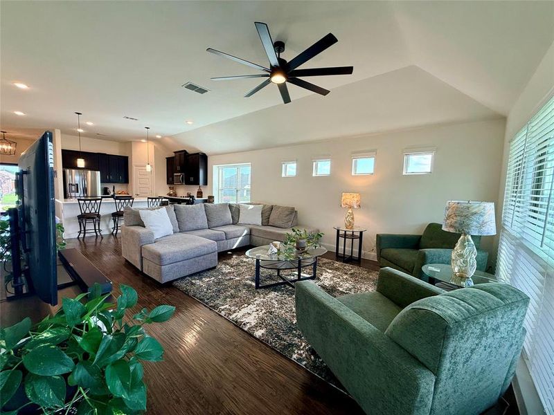 Open-concept living area featuring wood-finish flooring, vaulted ceilings, and a contemporary ceiling fan Open-concept living area featuring wood-finish flooring, vaulted ceilings, and a contemporary ceiling fan