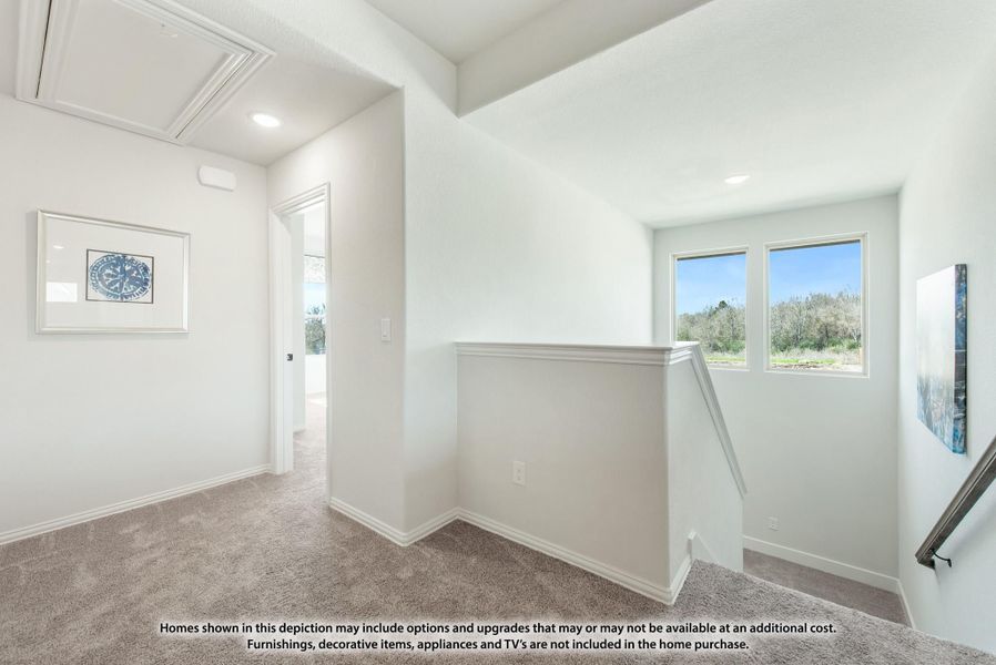 Upstairs hallway landing with carpet, stair railing, two windows, and open doorway to adjacent room