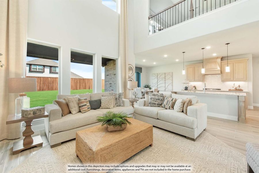 Open-concept living room with two-story ceiling, two sofas, and kitchen visible in background Open-concept living room with two-story ceiling, two sofas, and kitchen visible in background