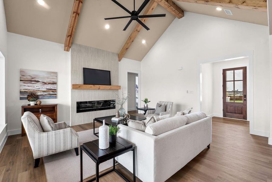 Living room with high vaulted ceiling, a large fireplace, beam ceiling, a ceiling fan, and dark wood finished floors Living room with high vaulted ceiling, a large fireplace, beam ceiling, a ceiling fan, and dark wood finished floors