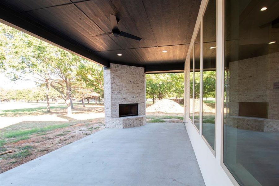 View of patio featuring an outdoor brick fireplace and ceiling fan