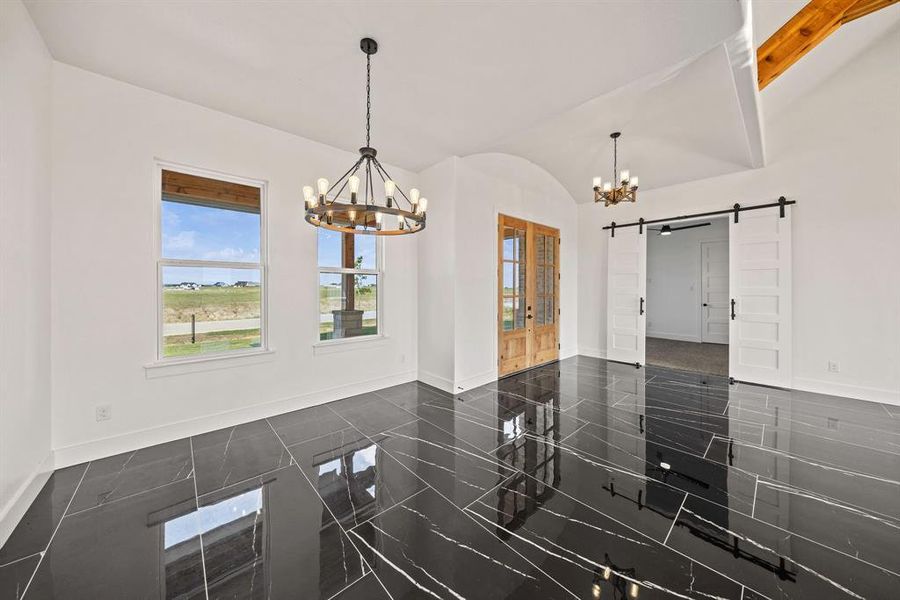 Spare room featuring a chandelier, a barn door, baseboards, and lofted ceiling Spare room featuring a chandelier, a barn door, baseboards, and lofted ceiling