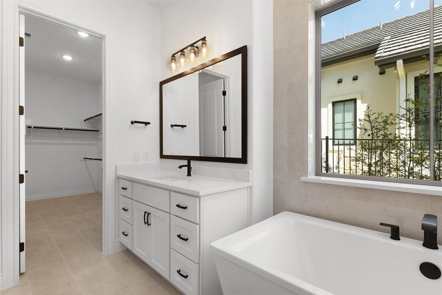 Bathroom featuring a white vanity with a rectangular sink, a dark framed mirror, and a soaking tub with dark fixtures