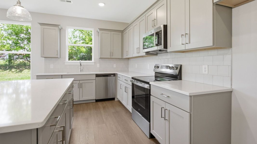 Kitchen with light cabinetry, quartz countertops, tile backsplash, and pendant lighting Kitchen with light cabinetry, quartz countertops, tile backsplash, and pendant lighting