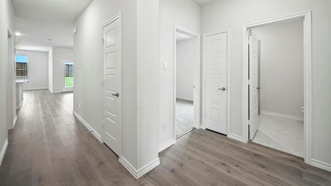 Hallway featuring wood-finish flooring, white paneled doors, and light gray wall paint