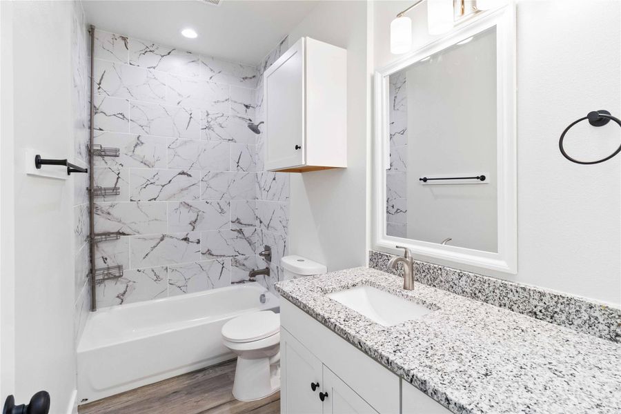 Full bath with bathtub / shower combination, vanity, and light wood-style flooring