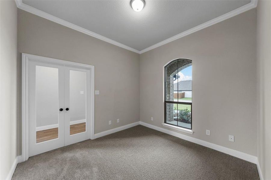 Carpeted room featuring a single arched window with exterior stone detailing