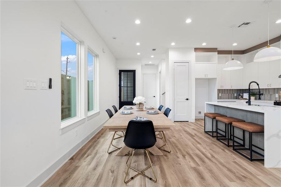 An elegant dining space positioned between the kitchen and living area, featuring a statement light fixture and ample space for a large table.