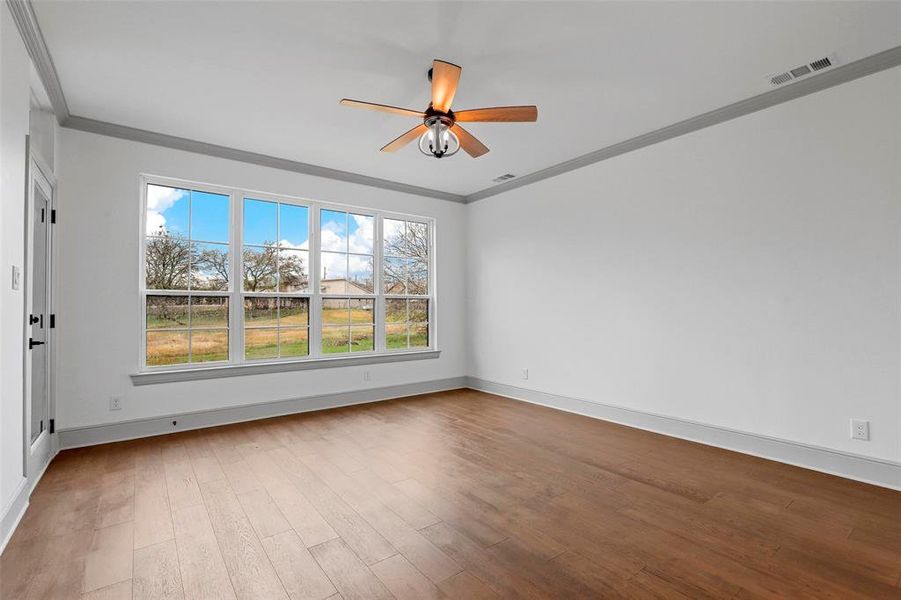 Unfurnished room with hardwood / wood-style flooring, ornamental molding, and ceiling fan