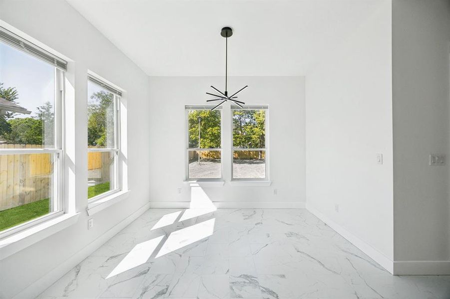 Unfurnished dining area featuring a chandelier and light marble finish flooring