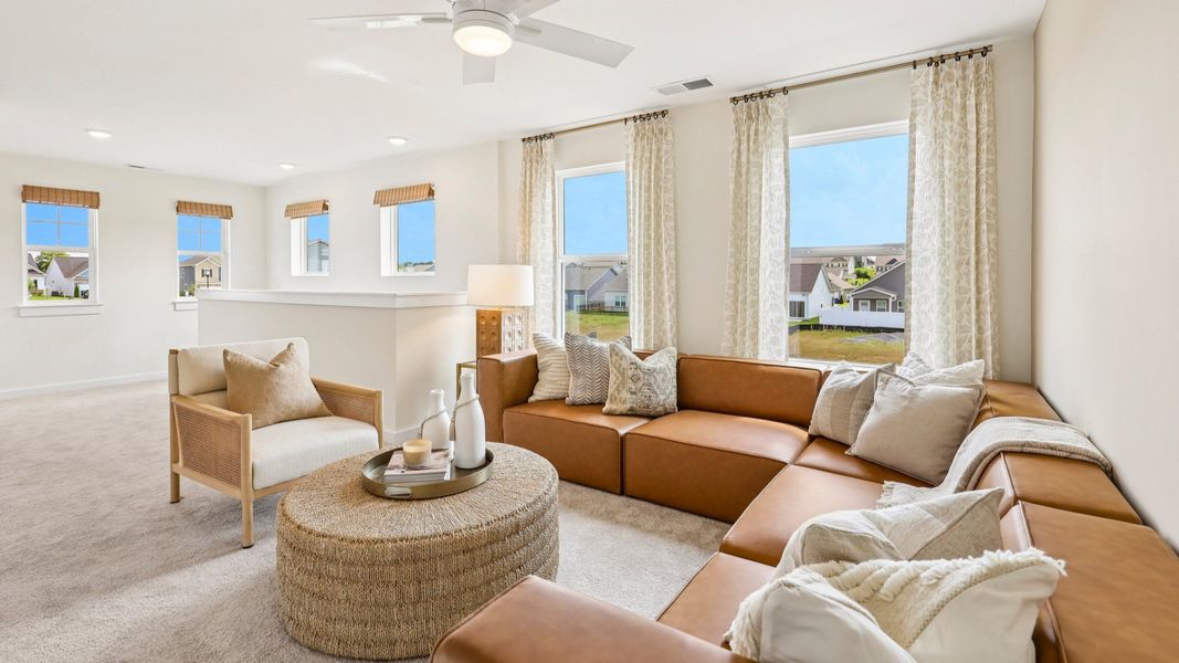 Loft with carpet, ceiling fan, and windows
