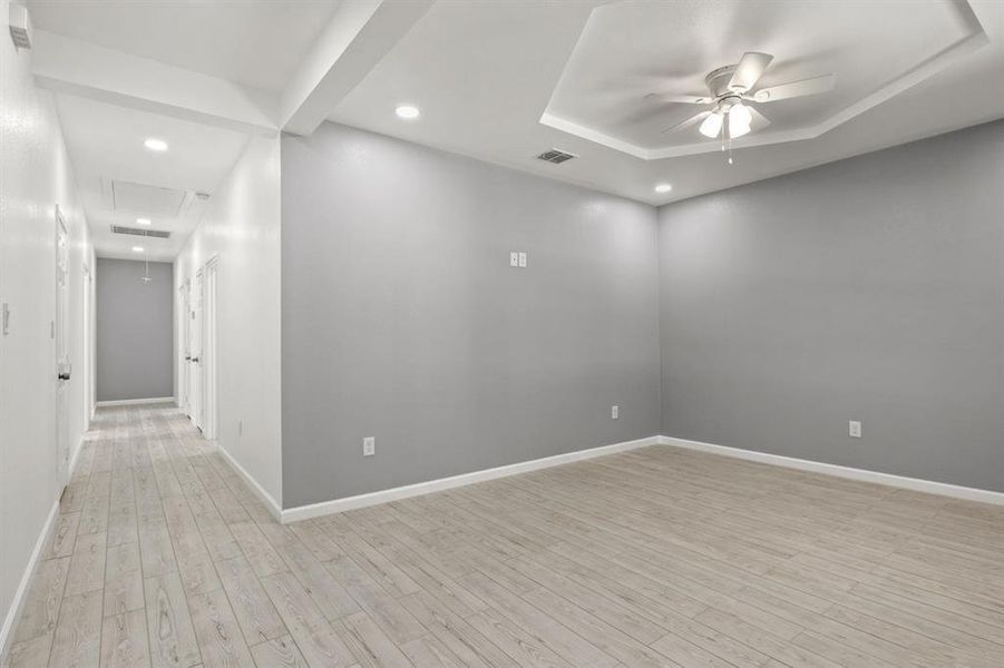 Empty room with light wood-style flooring, recessed lighting, a raised ceiling, and ceiling fan