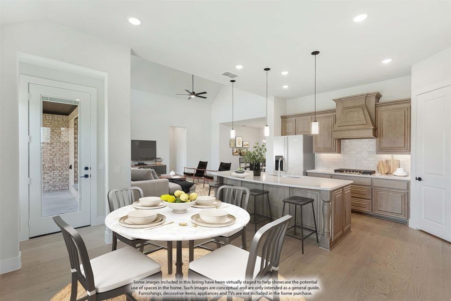 Open-concept kitchen and dining area with tan cabinets, large island, pendant lights, and round dining table on hardwood floors Open-concept kitchen and dining area with tan cabinets, large island, pendant lights, and round dining table on hardwood floors