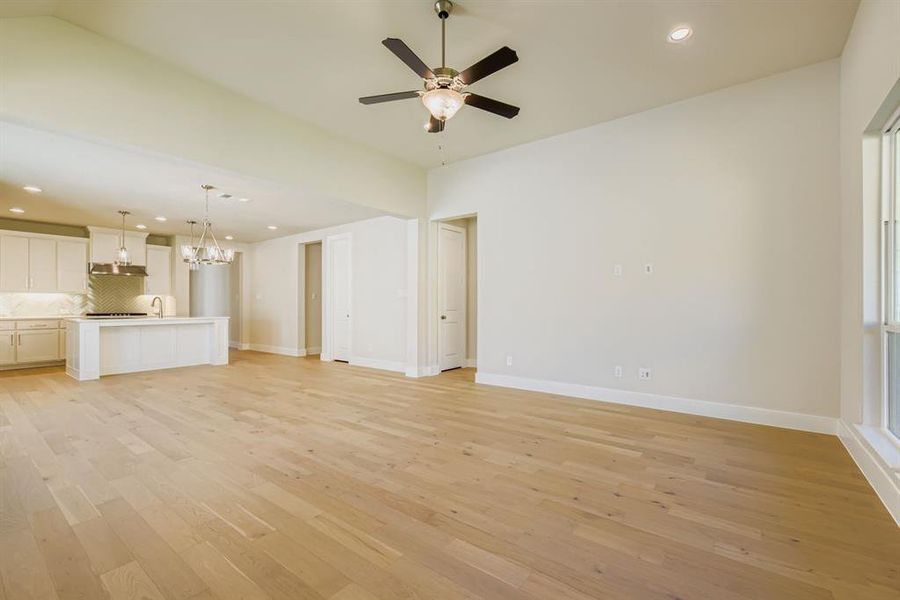 Unfurnished living room with recessed lighting, light wood-style floors, a chandelier, and ceiling fan