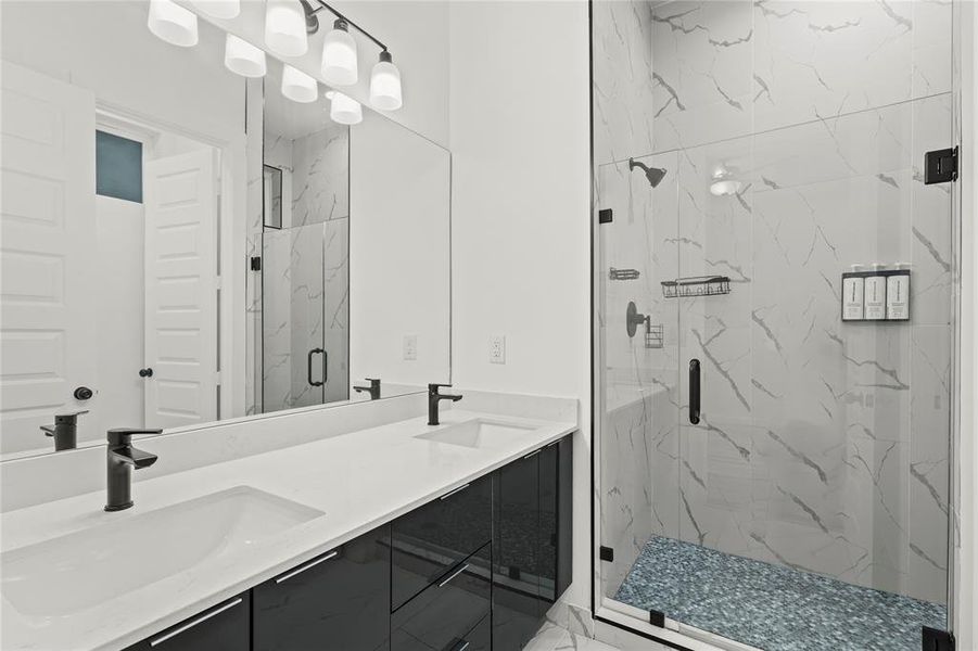 Full bathroom with a marble finish shower and double vanity Full bathroom with a marble finish shower and double vanity