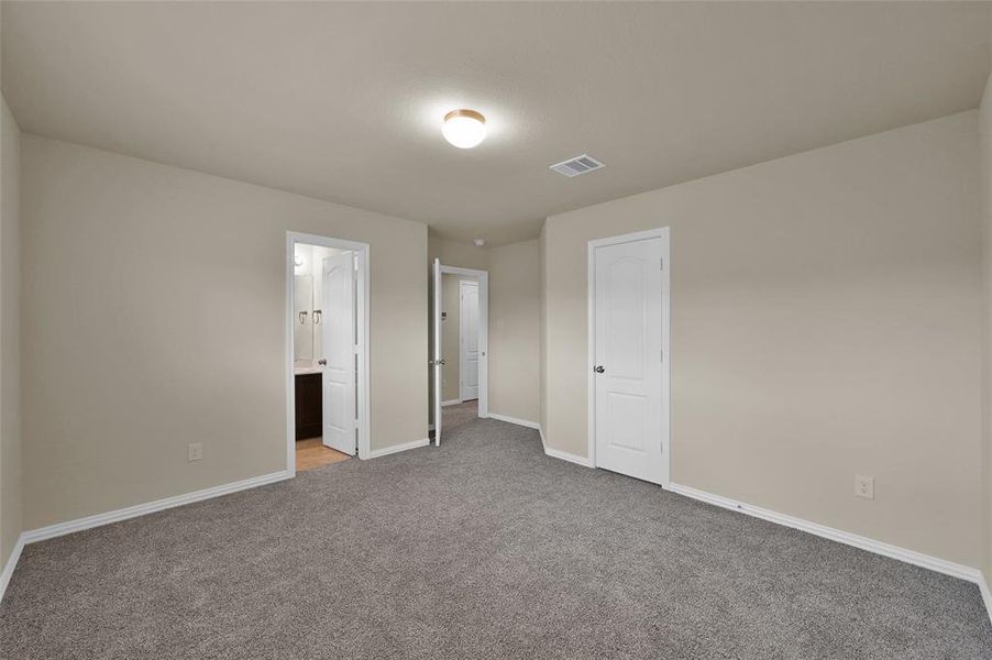 This is a spacious, carpeted room with neutral walls and ensuite bathroom.