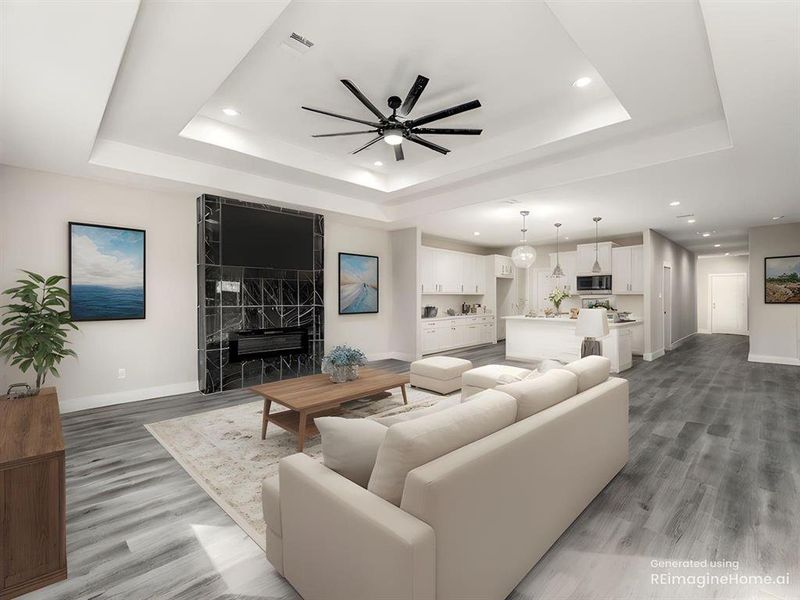 Living area featuring a premium fireplace, ceiling fan, light wood finished floors, recessed lighting, and a raised ceiling Living area featuring a premium fireplace, ceiling fan, light wood finished floors, recessed lighting, and a raised ceiling