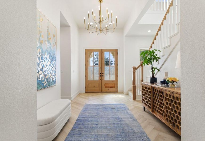 Foyer entrance featuring french doors, a textured wall, stairway, a chandelier, and recessed lighting