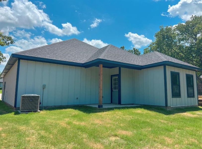 Rear view of property featuring a lawn and cooling unit