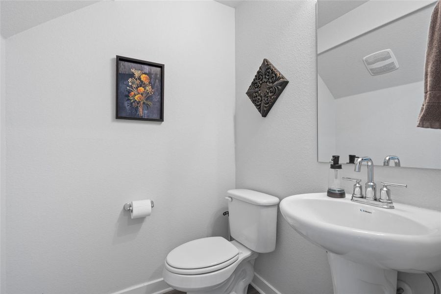 Half bath featuring toilet, baseboards, and a sink Half bath featuring toilet, baseboards, and a sink