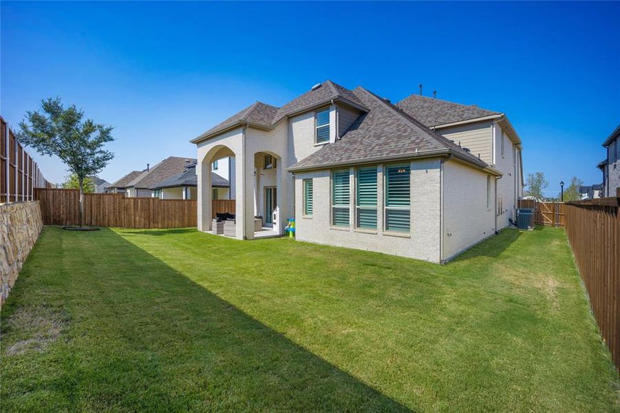 Rear view of property featuring a yard, a patio area, and central AC unit