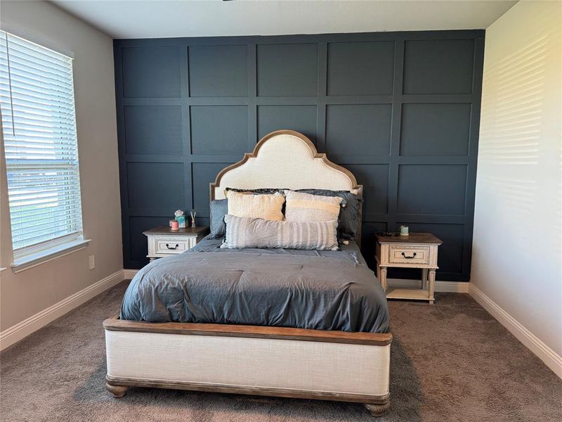 Carpeted bedroom featuring a decorative wall Carpeted bedroom featuring a decorative wall