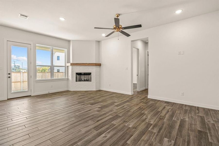 Unfurnished living room featuring dark wood-type flooring, baseboards, a ceiling fan, recessed lighting, and a brick fireplace