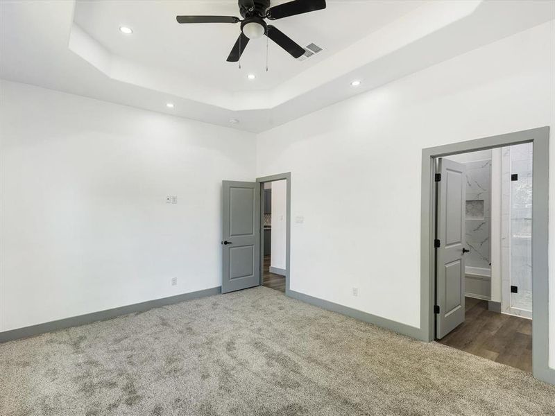Unfurnished bedroom featuring a tray ceiling, carpet floors, recessed lighting, ceiling fan, and ensuite bathroom Unfurnished bedroom featuring a tray ceiling, carpet floors, recessed lighting, ceiling fan, and ensuite bathroom