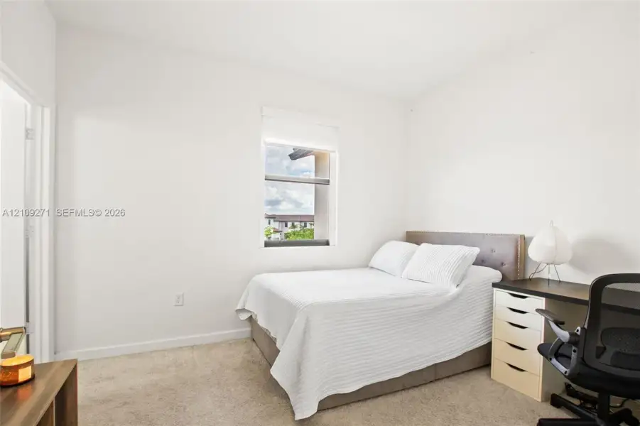 Neutral-toned interior space featuring wall-to-wall carpeting and a single window with a roller shade