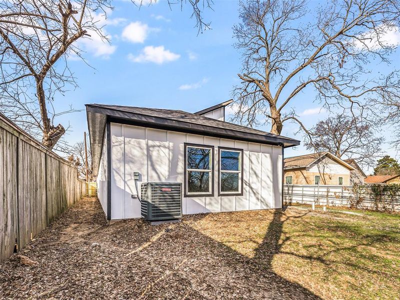 Rear view of house with a lawn, cooling unit, and a shed