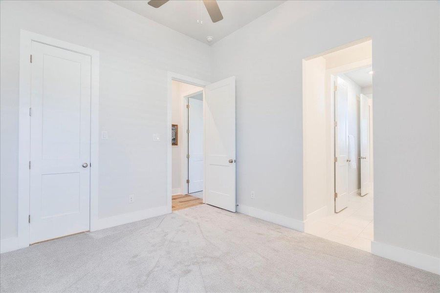 Unfurnished bedroom with light colored carpet and a ceiling fan Unfurnished bedroom with light colored carpet and a ceiling fan