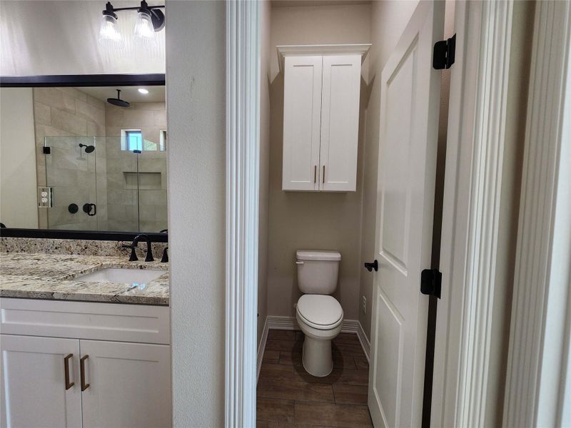 Bathroom featuring a shower stall, dark wood finished floors, and vanity