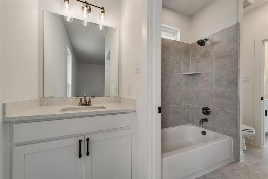 Full bathroom with tiled shower / bath, vanity, toilet, and tile flooring