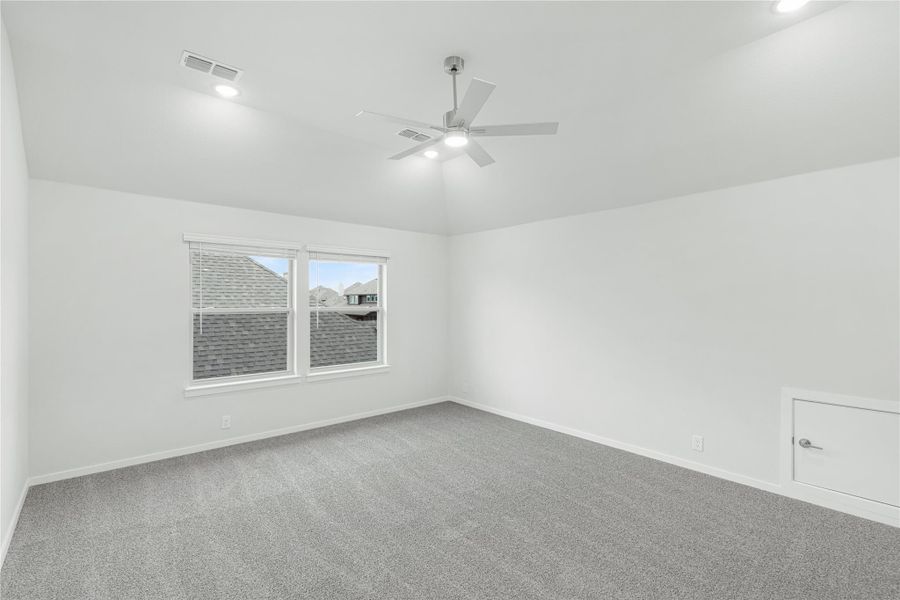 Empty bedroom with gray carpet, ceiling fan, white walls, and a double window