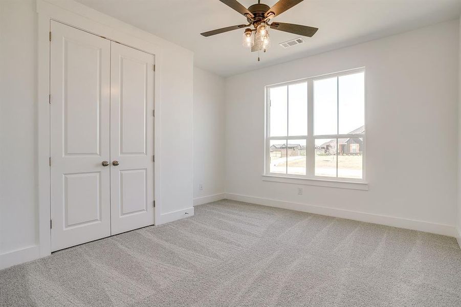 Unfurnished bedroom featuring light carpet, a ceiling fan, and a closet Unfurnished bedroom featuring light carpet, a ceiling fan, and a closet
