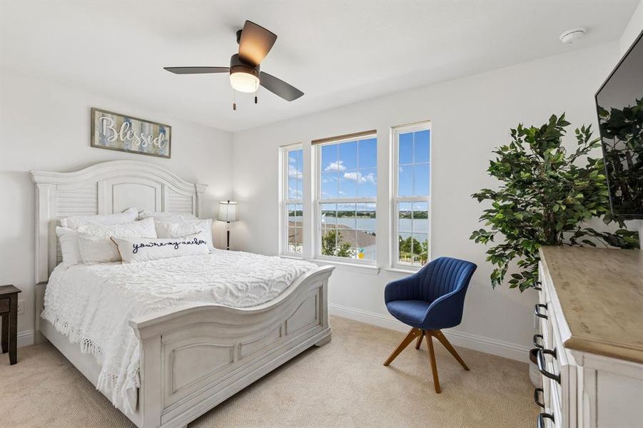 A bright and inviting secondary bedroom featuring large windows, soft natural light, and scenic lake views that add a peaceful touch to everyday living.