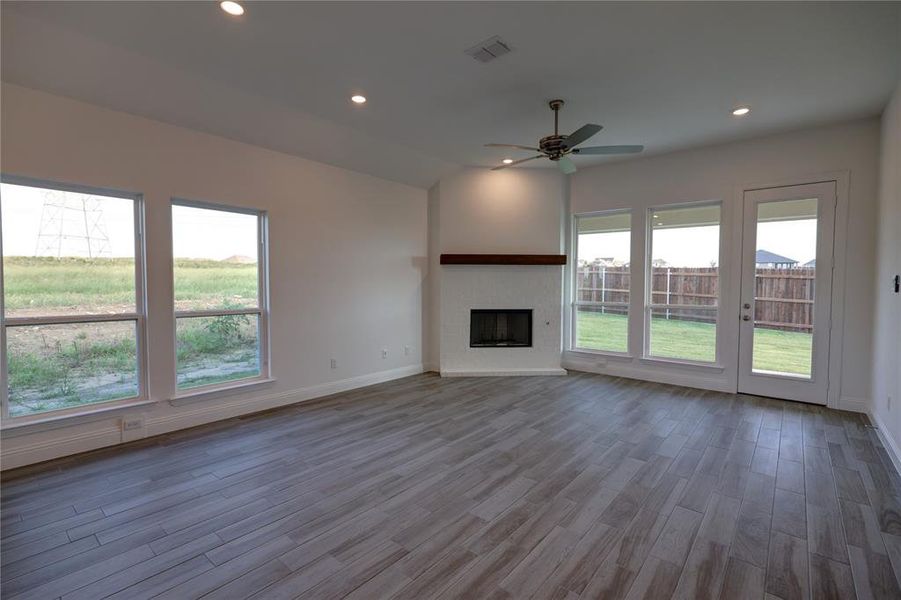 Unfurnished living room with ceiling fan, wood finished floors, recessed lighting, a fireplace, and vaulted ceiling Unfurnished living room with ceiling fan, wood finished floors, recessed lighting, a fireplace, and vaulted ceiling