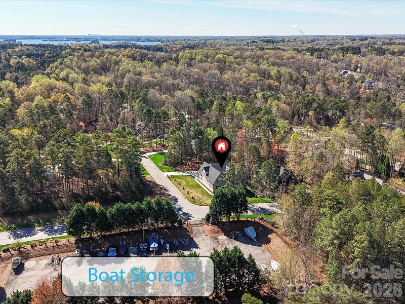 Aerial view showcasing the home’s prime location in a wooded community with nearby lake access and convenient neighborhood boat storage.