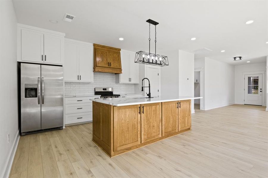 Kitchen featuring brown cabinetry, stainless steel appliances, white cabinets, decorative backsplash, and recessed lighting