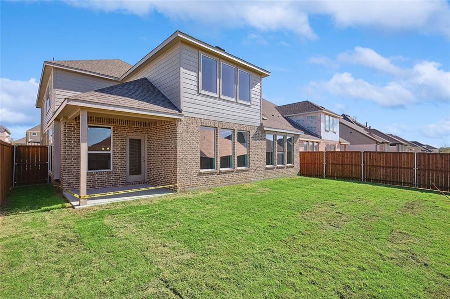 Rear view of property with a lawn and a patio