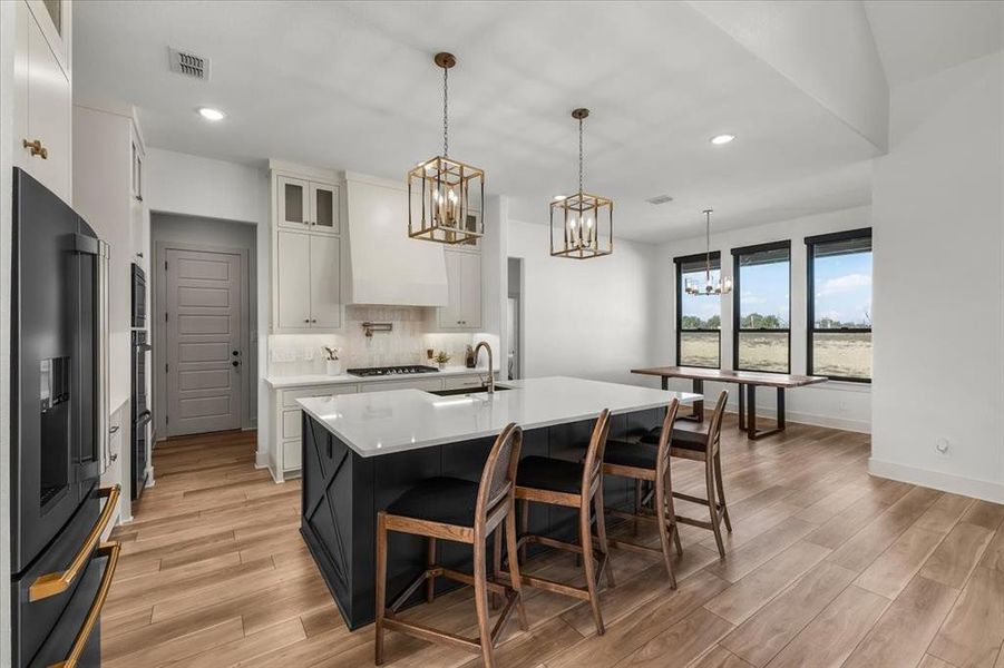 Upgraded vertical clay tile backsplash, black painted island, and glass door cabinet uppers provide luxurious finishes.