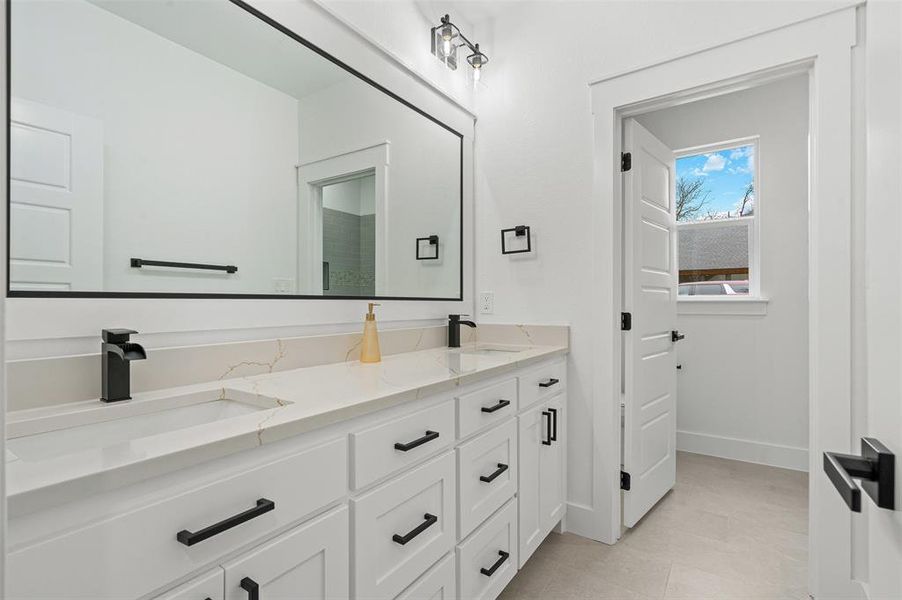 Bathroom featuring double vanity, baseboards, and a sink