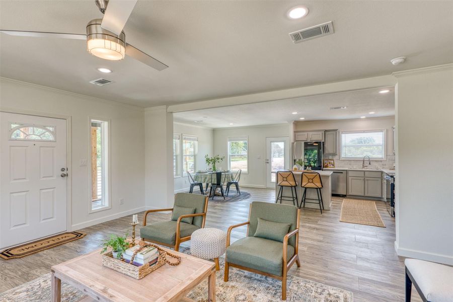 An inviting open-concept living space features wood-look laminate flooring and recessed lighting, seamlessly connecting to the kitchen and dining areas. An inviting open-concept living space features wood-look laminate flooring and recessed lighting, seamlessly connecting to the kitchen and dining areas.