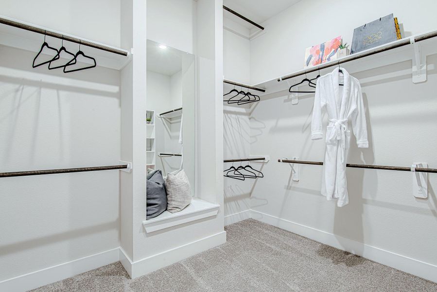 This expansive walk-in closet boasts custom shelving, double rods, and even a built-in bench with mirror—style and storage in one.