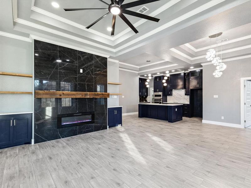 Unfurnished living room featuring crown molding, a fireplace, ceiling fan, recessed lighting, and light wood-type flooring Unfurnished living room featuring crown molding, a fireplace, ceiling fan, recessed lighting, and light wood-type flooring