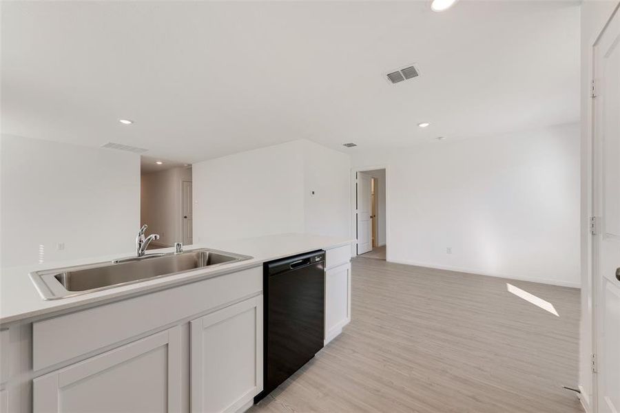 Kitchen featuring dishwasher, white cabinets, light hardwood / wood-style flooring, and sink