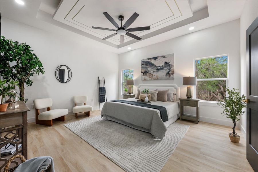 Bedroom featuring light wood finished floors, ceiling fan, recessed lighting, and a raised ceiling Bedroom featuring light wood finished floors, ceiling fan, recessed lighting, and a raised ceiling