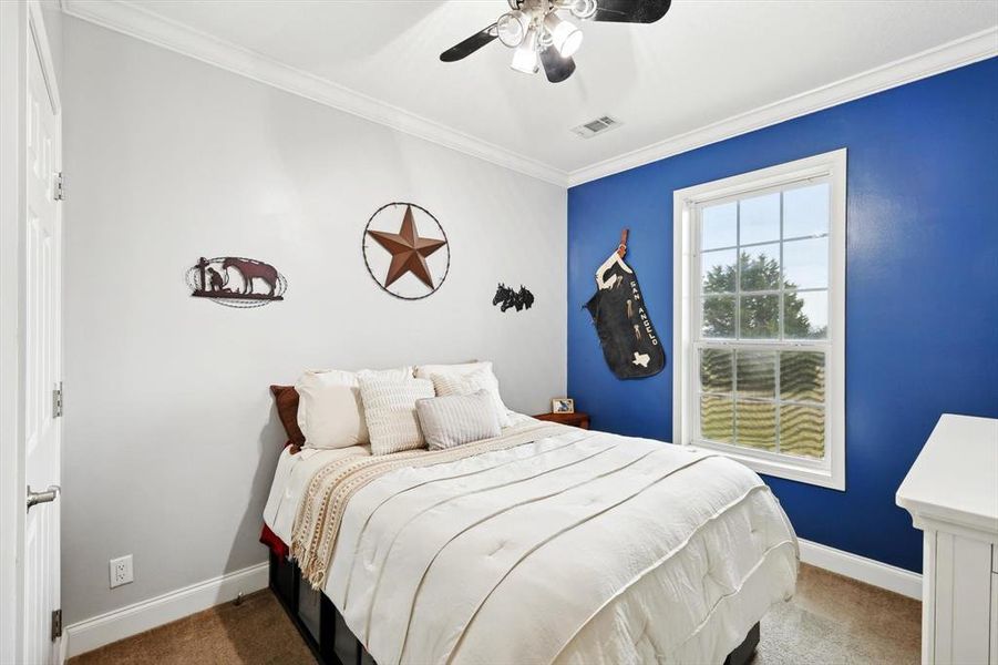 Carpeted bedroom with ornamental molding and ceiling fan