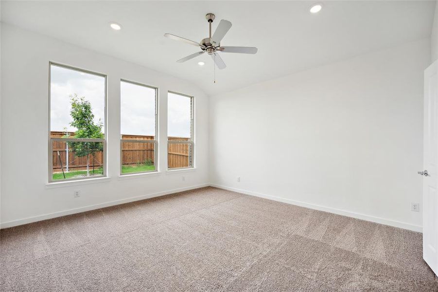 Carpeted empty room featuring ceiling fan and vaulted ceiling